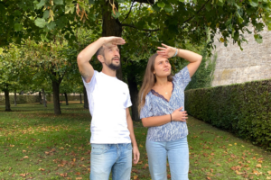 Mann und Frau stehen im Park und halten die Hand über die Augen, um in die Ferne zu schauen.